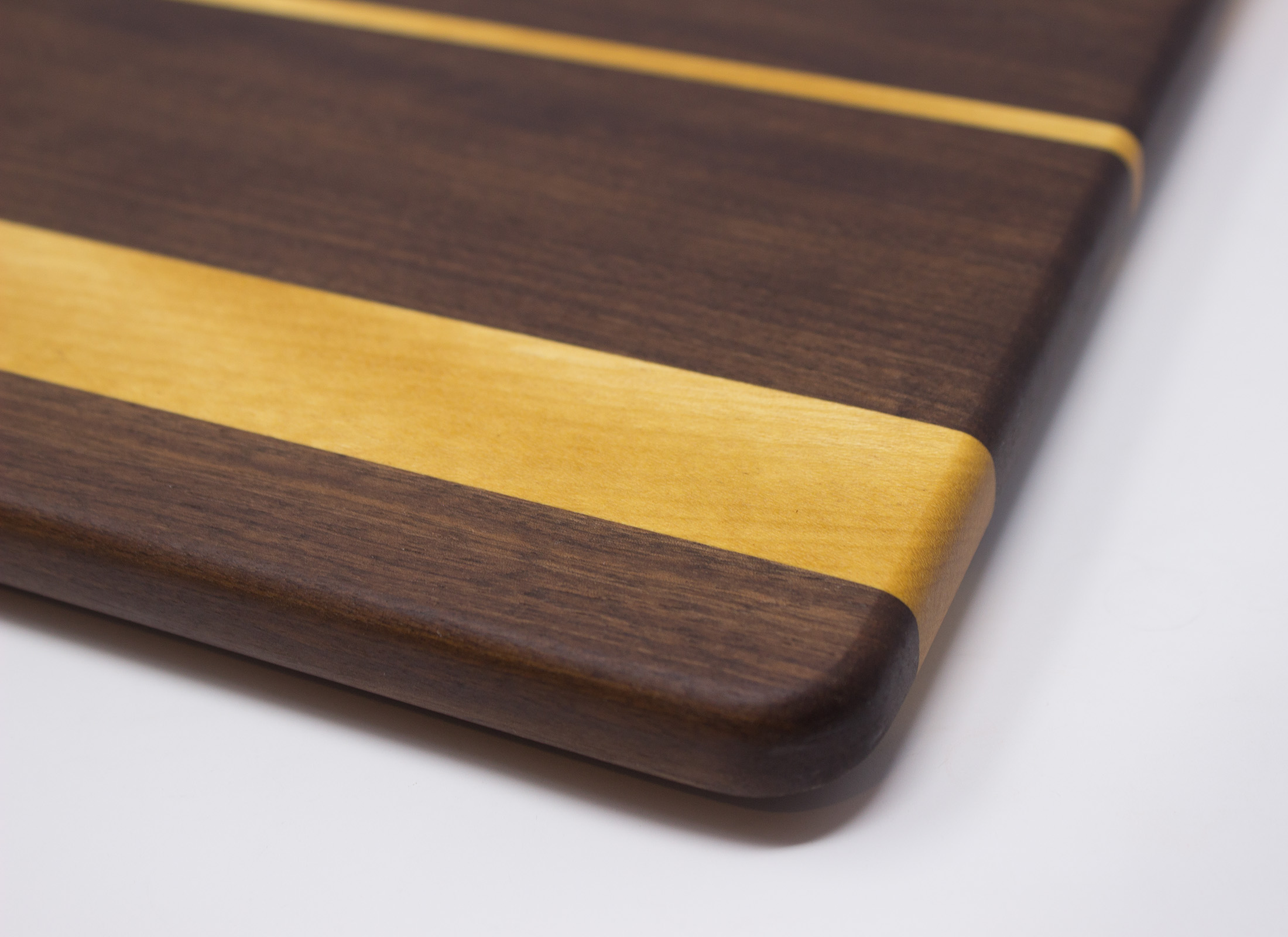 https://www.rockfordwoodcrafts.com/wp-content/uploads/Walnut-with-Three-Yellow-Stripes-Cutting-Board-Corner-Close-Up.jpg